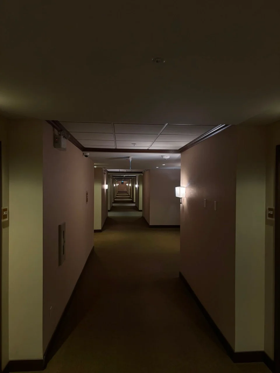 Long hallway with warm wall lights, dark trim and carpeted floor