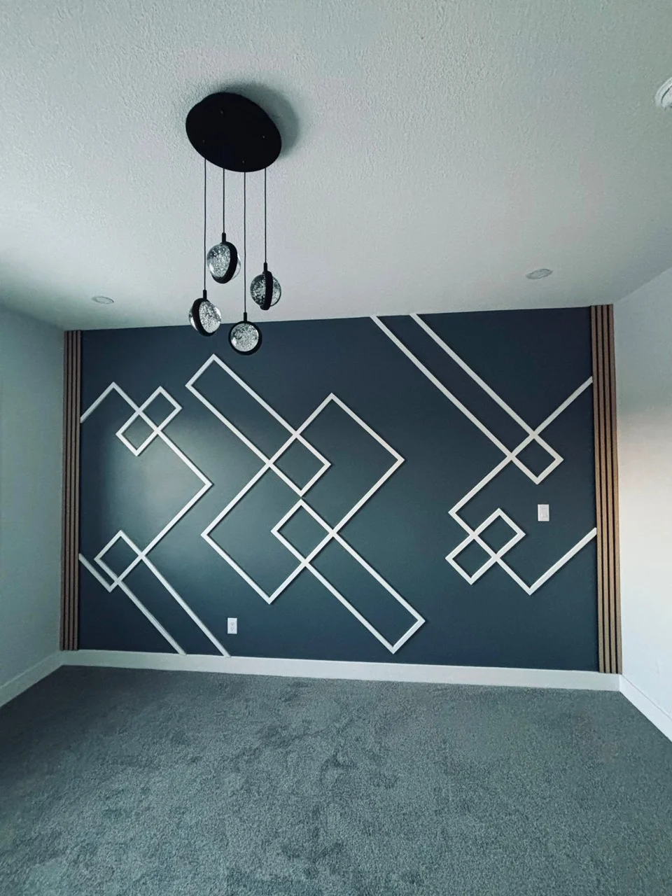 Dark blue feature wall with white geometric trim, narrow slatted edges and pendant lights