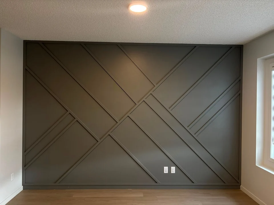 Charcoal feature wall with intersecting diagonal trim and wood-toned flooring