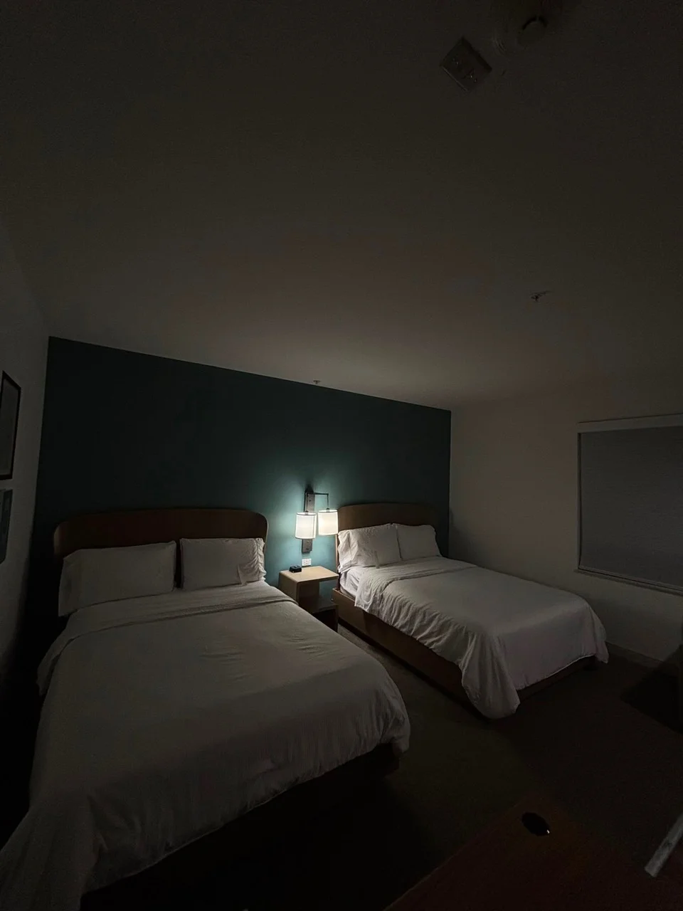 Guest room with two beds, a dark accent wall and a central wall light